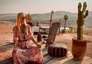 una donna seduta su un tavolo vicino al cactus di Agafay Luxury camp a Marrakech