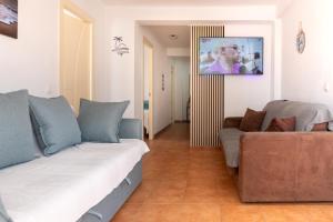 a living room with a couch and a tv on the wall at Apartamento ROMA in Torre del Mar