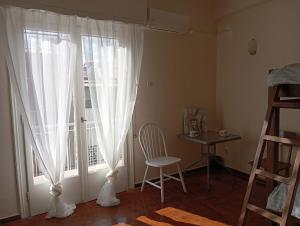 アテネにある4 Single beds room 5' from metroの窓、椅子、テーブルが備わる客室です。