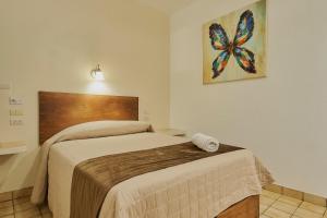 a bedroom with a bed with a butterfly painting on the wall at Hotel Cervantino in Tapachula