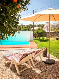 a pair of chairs under an umbrella next to a pool at Casa do Lado in Reguengo
