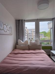 a bed with white pillows in a room with a window at Modern Two-Bedroom apartment with Balcony in Cologne in Cologne