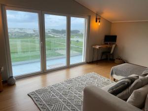 un salon avec un canapé et une grande fenêtre dans l'établissement Beachfront Costa Nova Villa - 3 BR Apartment, à Gafanha da Encarnação