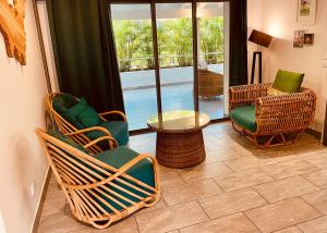a living room with wicker chairs and a table at Villa Ti Pop - Corossol in Anse des Flamands