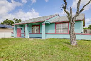 a blue and pink house with a tree in the yard at Mins to the Coast Port St Lucie Home with Lanai! in Fort Pierce