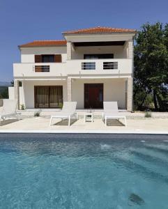 a house with two chairs and a swimming pool at Family friendly house with a swimming pool Posedarje, Novigrad - 23578 in Posedarje