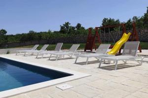 a group of chairs and a slide next to a pool at Family friendly house with a swimming pool Posedarje, Novigrad - 23578 in Posedarje