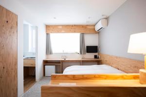 a bedroom with a bed and a desk and a window at イリゴアパートメントホテル in Hirosaki