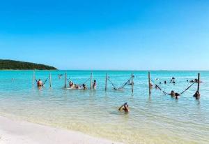 a group of people in the water at the beach at Suíte 2 caminho do mirante in Iguaba Grande