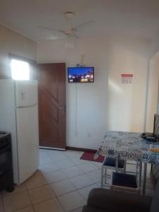 a kitchen with a table and a television on the wall at Lola Apart in Bombinhas