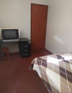 a bedroom with a bed and a tv on a desk at Piratex alojamiento in Huarmey