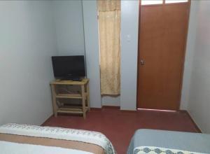 a room with a bed and a television and a door at Piratex alojamiento in Huarmey +4 photos