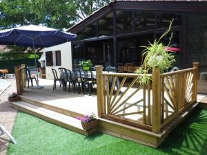 una terraza de madera con sillas y sombrilla en Maison Champagne, en Escource