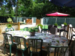 una mesa, sillas y una sombrilla en el patio en Maison Champagne, en Escource