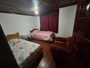 a small room with two beds and a chair at Lugar tranquilo in Pititic
