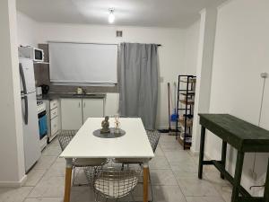 una cocina con una mesa blanca con sillas y una pantalla en Depto Los Troncos, en Tandil 4 fotos más