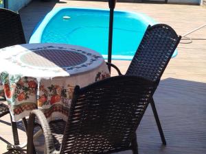 a table and chair next to a swimming pool at Pousada Bella Montanha in Lauro Müller