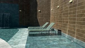 two chairs sitting on the side of a brick wall at Aline Duque - Flat no centro de Porto de Galinhas por Yolo in Porto De Galinhas