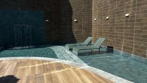 a couple of chairs sitting next to a brick wall at Aline Duque - Flat no centro de Porto de Galinhas por Yolo in Porto De Galinhas