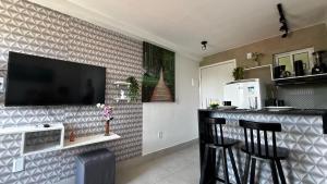 a kitchen with a bar with a television on a wall at Aline Duque - Flat no centro de Porto de Galinhas por Yolo in Porto De Galinhas +51 photos