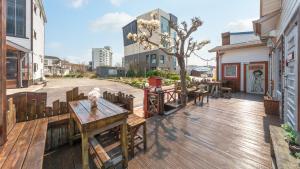 Una terraza de madera con una mesa y sillas. en Sokcho Seohyeon Ine Pension, en Sokcho