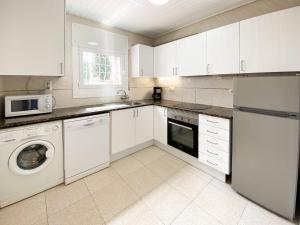 a kitchen with white cabinets and a washer and dryer at Villa in L Escala near Platja d'Empúries in L'Escala +12 photos