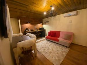 ein Wohnzimmer mit einem roten Sofa und einem Tisch in der Unterkunft Chales Gramado Exclusive in Gramado