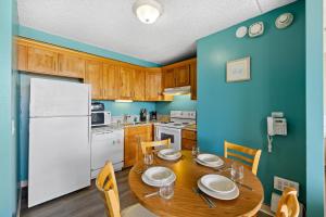 a kitchen with a wooden table and a white refrigerator at Royal Kuhio 2309 - Spacious Studio with Stunning Ocean Views in the Heart of Waikiki! in Honolulu