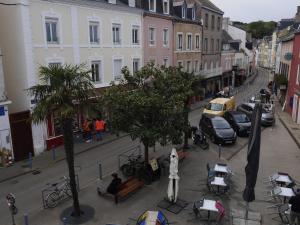 una strada cittadina con auto parcheggiate, tavoli e sedie di Appartement cosy 2 chambres, cœur de Le Palais, proche commerces et plage - FR-1-418-268 a Le Palais