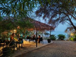 a group of people sitting at tables under a straw umbrella at Turtle Hill Patnem in Canacona