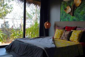 a bedroom with a bed with colorful pillows and a window at Turtle Hill Patnem in Canacona