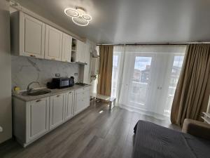 eine Küche mit weißen Schränken und einem großen Fenster in der Unterkunft COZY studiou Mamaia Nord by Alezzi in Mamaia Nord – Năvodari