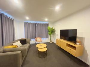 ein Wohnzimmer mit Couch und Flachbildfernseher in der Unterkunft Rotorua Sunshine Brand New 4 Bedroom house in Rotorua