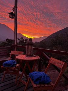 un tavolo e sedie su una terrazza con tramonto di Cabaña el Maiten a Guayacán