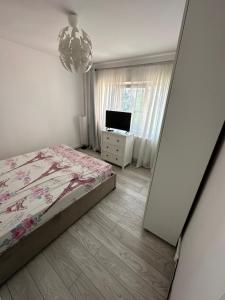 Schlafzimmer mit einem Bett, einem TV und einem Kronleuchter in der Unterkunft CMD Apartament 2 camere in Buzău