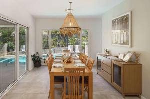 a dining room with a table and chairs and a chandelier at Pet friendly Holiday home with pool on Alex in Alexandra Headland