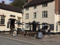 a building with tables and umbrellas in front of it at The Swan Taphouse in Ironbridge