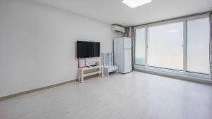 an empty living room with a television and a large window at Sokcho World Pet-Friendly (Paid) Pension in Sokcho