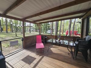 a screened porch with a pink chair and a glass table at Domek letniskowy nr 16 - jezioro Głębokie in Międzyrzecz