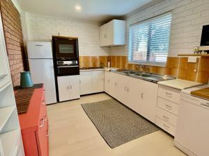 cocina con armarios blancos, fregadero y nevera en Beachfront Bliss on Collingwood Beach, en Vincentia