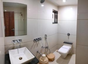 une salle de bain blanche avec un lavabo et des toilettes dans l'établissement Hotel Zenith, à Surate