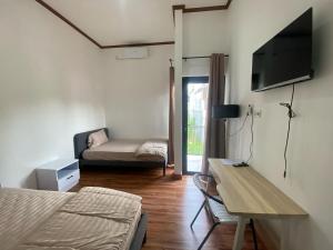 ein Schlafzimmer mit einem Bett, einem Fernseher und einer Couch in der Unterkunft EMWEKA Residence Balikpapan in Balikpapan