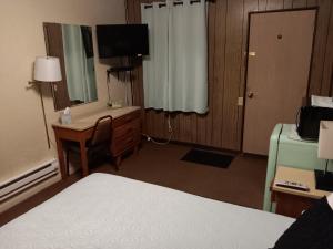 una camera d'albergo con un letto, una scrivania e una televisione di Crawford Motel a Springfield