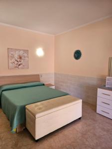 a bedroom with a bed and a ottoman in it at La Rosa dei Venti B&B in Chia