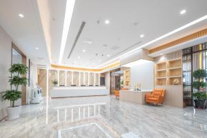 an office lobby with an orange chair and a desk at 万信r酒店上海崇明万达广场店 in Shanghai