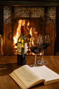 ヌワラエリヤにあるFerncliff Bungalowのワイン1本、暖炉付きのテーブルにグラス2杯
