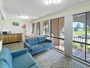 a living room with two blue couches and a kitchen at Charming 2-Bed Apartment with Bay Views in Batemans Bay