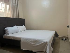 a bed with white sheets and pillows in a bedroom at White Ash 1 Berdroom Apartment in Kampala