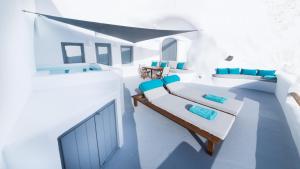 um quarto branco com cadeiras azuis e uma cama em Maregio Suites em Oia