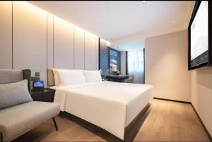 a bedroom with a large white bed and a chair at Atour Hotel Dalian Donggang Business District Harbor Plaza in Dalian